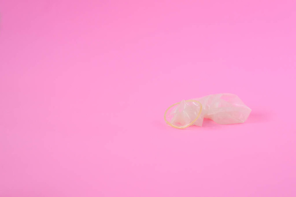 Condón usado sobre fondo de papel rosa con espacio de copia para texto. Salud reproductiva, anticoncepción y concepto de sexo seguro
 - Foto, Imagen