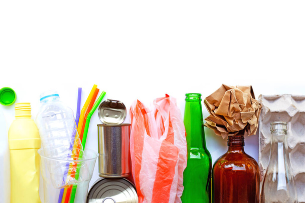 Утилизируемый мусор, пластиковая бутылка, стеклянная бутылка, канистра и лоток для яичной бумаги на фоне коричневой фанеры. Копирование пространства
 - Фото, изображение