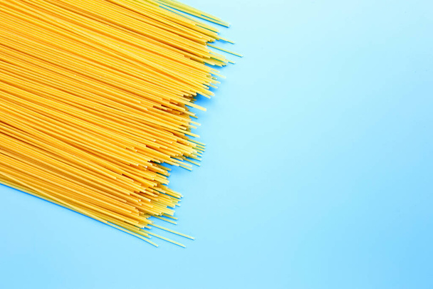 Żółte długie spaghetti na niebieskim tle. Przestrzeń kopiowania - Zdjęcie, obraz