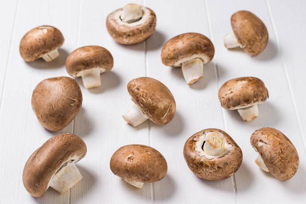 Muchos hongos reales esparcidos en una mesa de madera blanca. Comida vegetariana
. - Foto, imagen