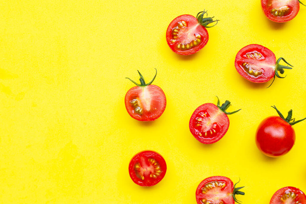 Φρέσκες ντομάτες, ολόκληρες και μισές κομμένες σε κίτρινο φόντο. Κορυφαία προβολή - Φωτογραφία, εικόνα