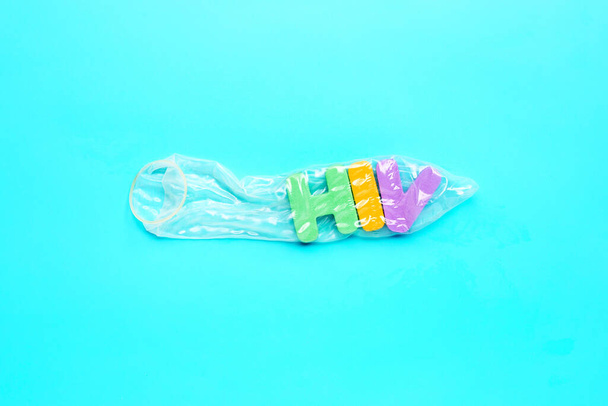 Kondom s "HIV" barevnou abecedou na modrém pozadí. Uložit koncept sexu, Topv view - Fotografie, Obrázek