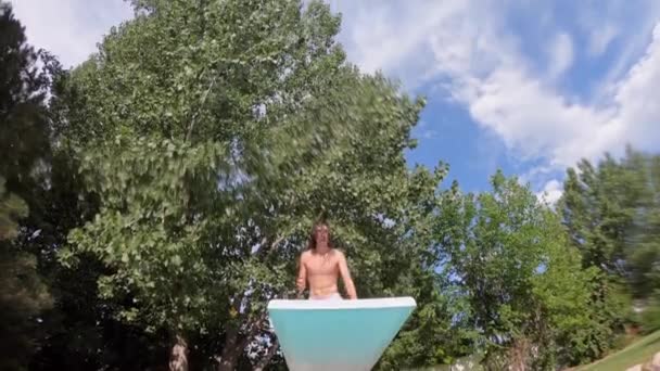Teenager doing a gainer into pool over the camera following him overhead. - Imágenes, Vídeo