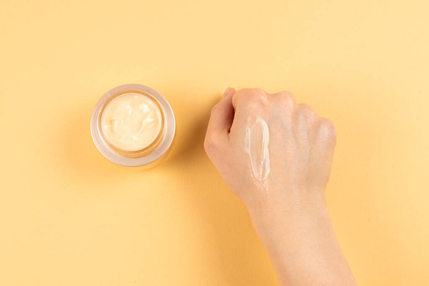 Hand cream and woman hands on a beige background. Copy space.  - Fotoğraf, Görsel
