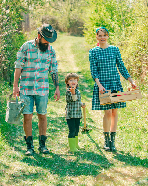 Young family with child having fun in nature. Life for family farmers in the countryside. Couple with son gardening in the backyard garden. - Foto, imagen
