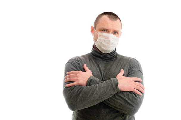 Concept isolate serious Caucasian man shows emotions with his hands in a medical mask in a gray sweater on a white background - Foto, Bild