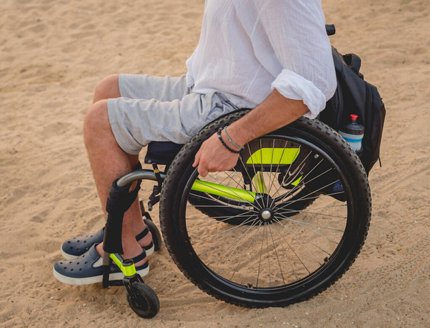 Vammainen mies pyörätuolissa rannalla
. - Valokuva, kuva