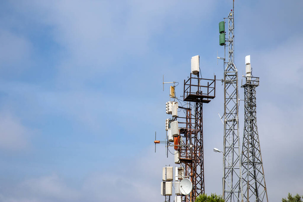 Sok telekommunikációs tornyok mobilhálózat 4g, Lte és 5 g antennák a magasság kiterjesztő tornyok ellen a napsütéses nappal ég felhők és másolás tér. - Fotó, kép