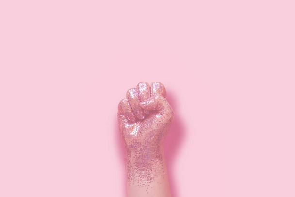 woman fist covered in pink glitter on pink background - Foto, Bild