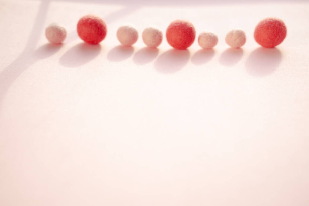 Bolas de lã são jogadas para baixo pelo método da agulha inclinada, espalhadas na parte superior do cartão postal em um fundo rosa liso
. - Foto, Imagem