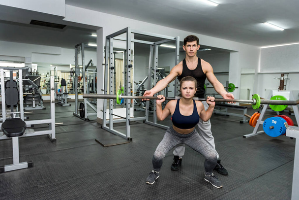 Trainer trainiert junge und schöne Frau im Fitnessstudio - Foto, Bild