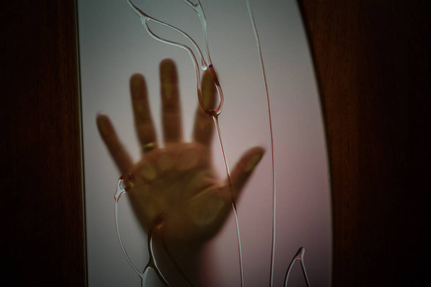 Mano humana detrás del vidrio esmerilado de la puerta, cerca
 - Foto, imagen