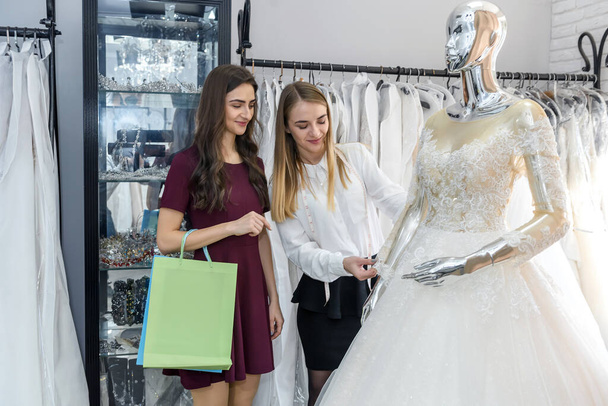 Bride with tailor choosing wedding dress in store - Foto, Imagen