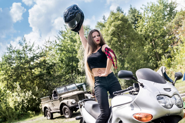 Femme avec un casque à la main, debout près de la moto
 - Photo, image
