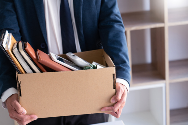 Sad Fired Young Employee businessmen hold boxes including pot plant and documents for personal belongings unemployment, resigned concept - Photo, Image