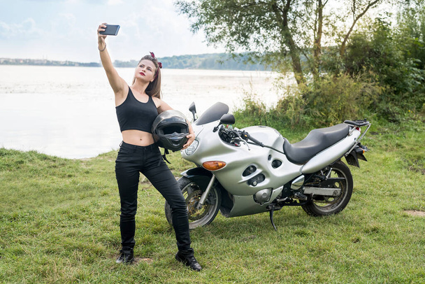 Mujer joven haciendo selfie en moto al aire libre
 - Foto, Imagen