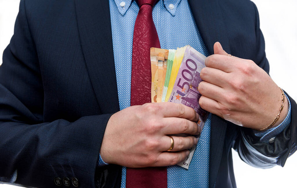 Homem que põe notas de euro no bolso do casaco
 - Foto, Imagem