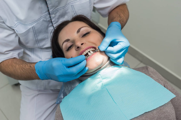 Zubař porovnávající barvu zubů pacienta se vzorkovačem - Fotografie, Obrázek