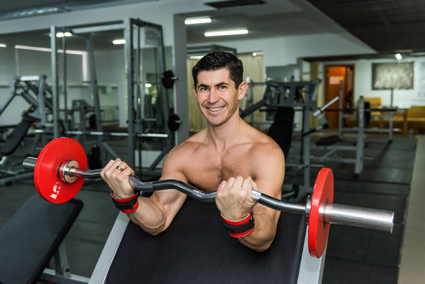 Young man lifting up barbell in gym - 写真・画像