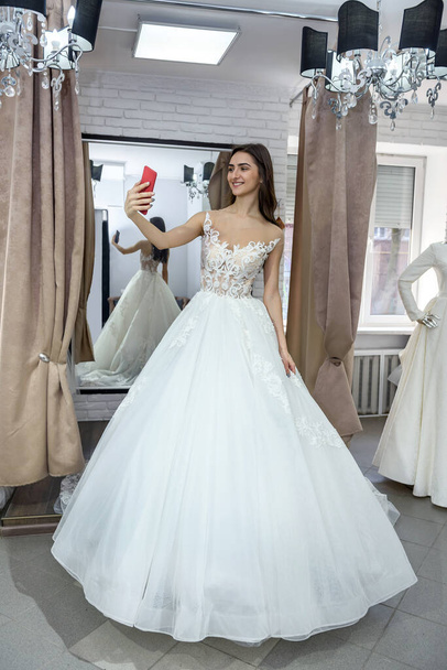 Giovane sposa che fa selfie in abito da sposa nel salone
 - Foto, immagini