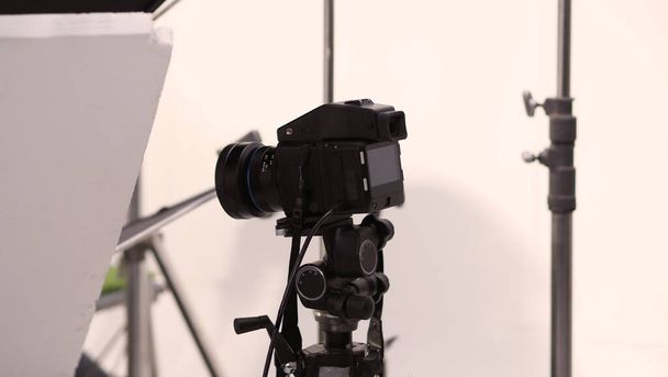 Stüdyoda, fotoğraf çekimi, yüksek çözünürlüklü video veya film çalışmaları için siyah beyaz softbox ve ışıklandırma setine sahip tripod ve profesyonel ekipman üzerine dijital kamera kurulumu - Fotoğraf, Görsel