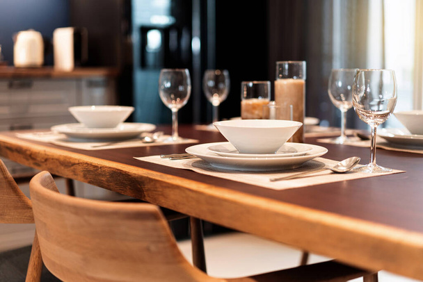 Elegante mesa de comedor en una mesa de madera con vajilla, cubiertos, utensilios, copas de vino y velas. Conjunto de mesa para comedor fino, servicio de hotel de comida de lujo
. - Foto, Imagen