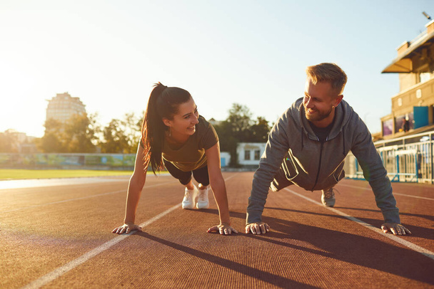 Young couple doing pushups in the stadium - Photo, image