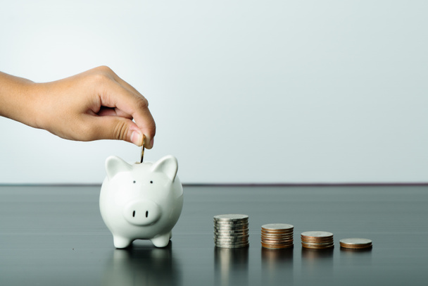 Economia de dinheiro e conceito de doação, criança colocar dinheiro em bonito banco piggy branco
 - Foto, Imagem