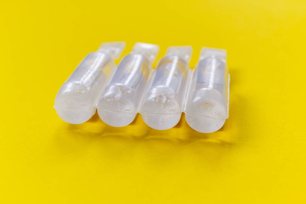 physiological serum ampoules on a yellow background. Nursing care - Photo, Image