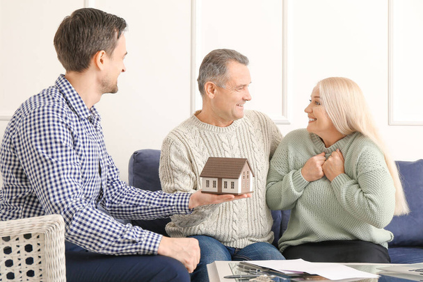 Male real estate agent working with mature couple indoors - Foto, Imagen