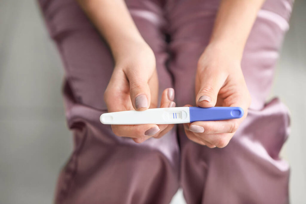 Mladá žena s těhotenským testem v koupelně, detailní záběr - Fotografie, Obrázek