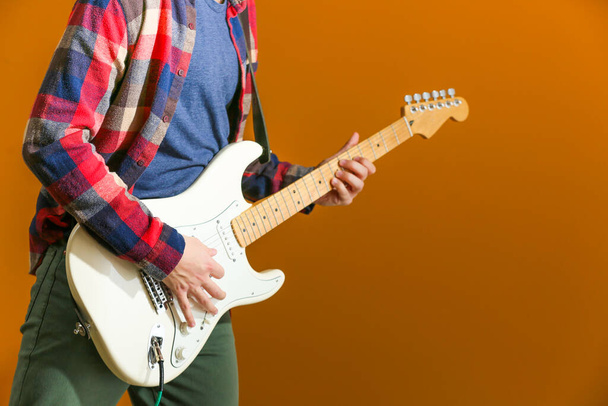 Jeune homme jouant de la guitare sur fond de couleur - Photo, image