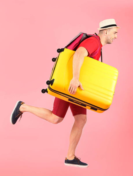 Running male tourist with luggage on color background - Photo, Image