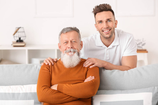 Portrait of senior man and his adult son at home - Photo, Image