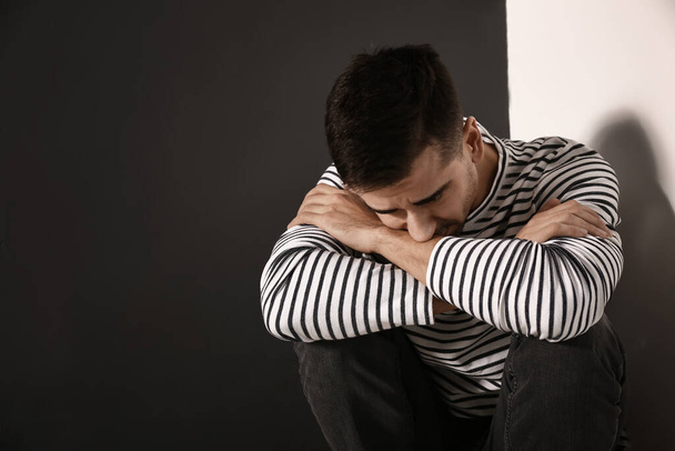 Mladý muž v depresi sedí u zdi - Fotografie, Obrázek