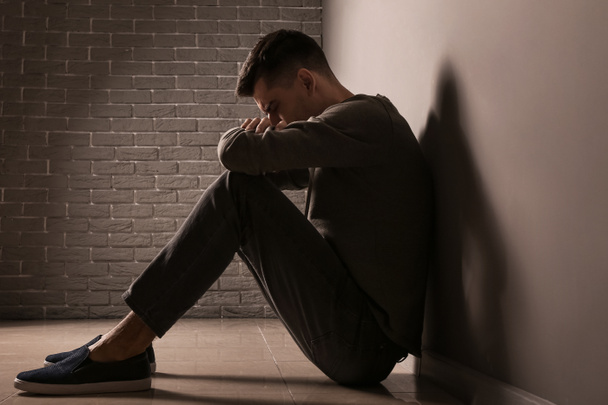 Depressziós fiatalember a szürke fal közelében - Fotó, kép