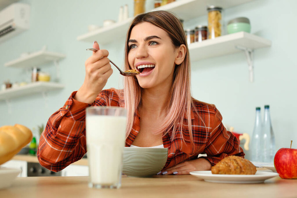 Красивая молодая женщина завтракает на кухне - Фото, изображение
