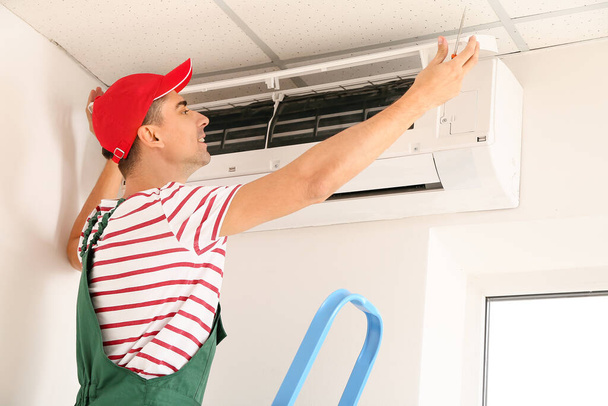 Techniker repariert Klimaanlage in Innenräumen - Foto, Bild
