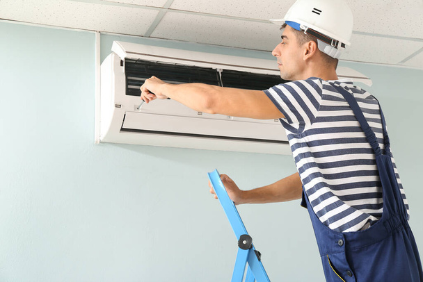 Male technician repairing air conditioner indoors - Фото, зображення