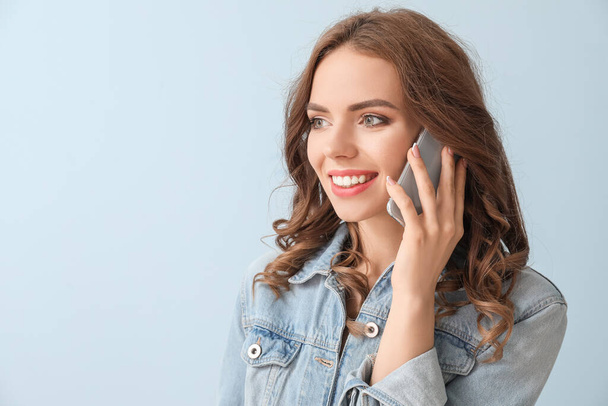 Young woman talking by mobile phone on color background - Photo, image