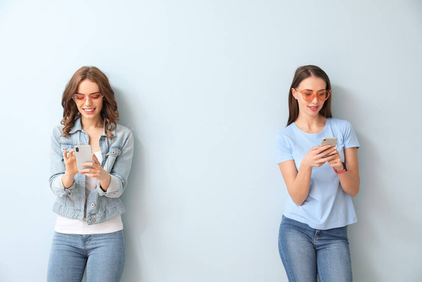 Young women with mobile phones on color background - Foto, afbeelding