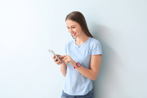 Jonge vrouw met mobiele telefoon op kleur achtergrond - Foto, afbeelding