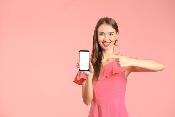 Jonge vrouw met mobiele telefoon op kleur achtergrond - Foto, afbeelding