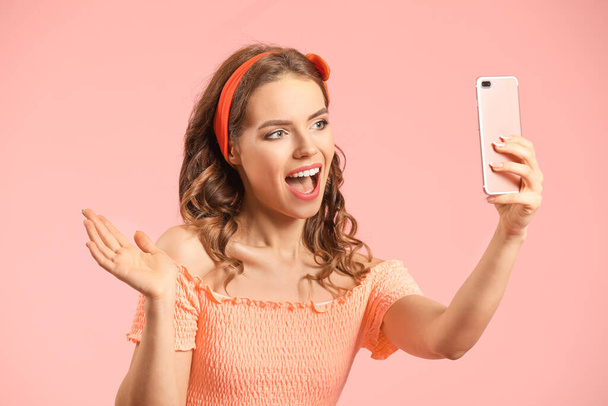 Fiatal nő mobiltelefon csinál szelfi a színes háttér - Fotó, kép