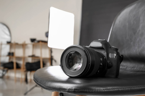 Μοντέρνα κάμερα σε καρέκλα σε επαγγελματικό φωτογραφικό στούντιο - Φωτογραφία, εικόνα