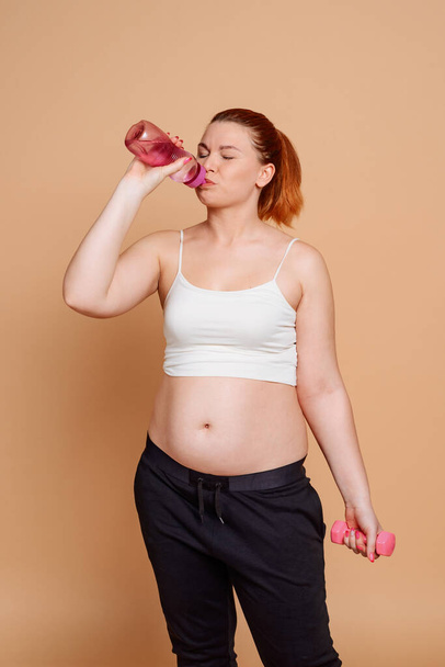 Woman drinking water after workout. Getting rid of belly fat - Fotó, kép