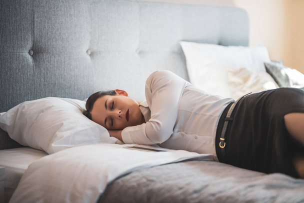 Unavená podnikatelka spí oblečená v hotelovém pokoji. - Fotografie, Obrázek