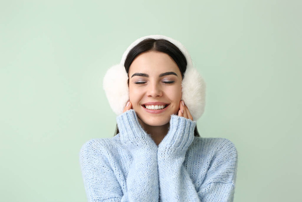 Beautiful young woman in warm sweater on color background - 写真・画像