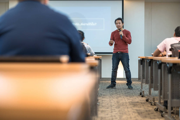 Азіатський промовець, який показує і представляє знання перед сценою через погляд аудиторії прослуховування в залі засідань або конференц-залі, семінар бізнес і концепція освіти - Фото, зображення