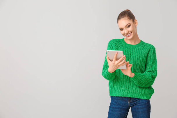 Junge Frau mit Tablet-Computer auf grauem Hintergrund - Foto, Bild